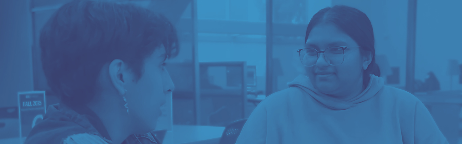 Tutor and student seated at table with blue duotone overlay